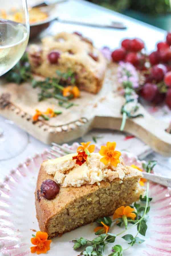 A slice of Olive Oil Cake with Polenta and Roasted Red Grapes slathered with baked ricotta 