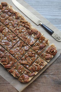 Pecan bars on parchment paper with a knife next to them