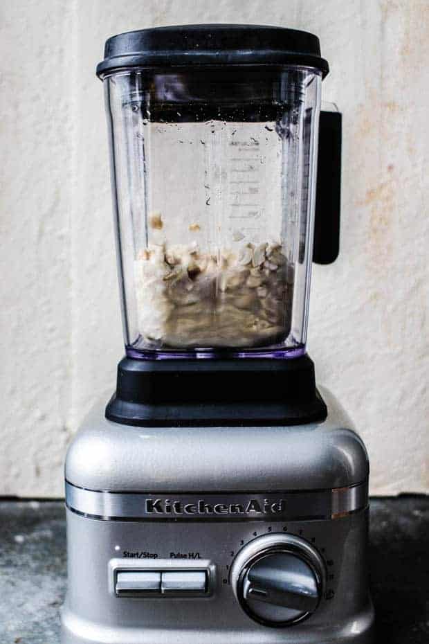 A kitchen aid blender filled with the ingredients to make cashew cream 