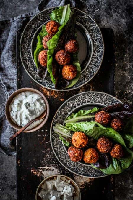 2 plates of sweet potato and millet falafel lettuce wraps next to bowl of homemade tzatziki