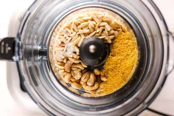 The ingredients for vegan Parmesan cheese in teh bowl of a food processor.