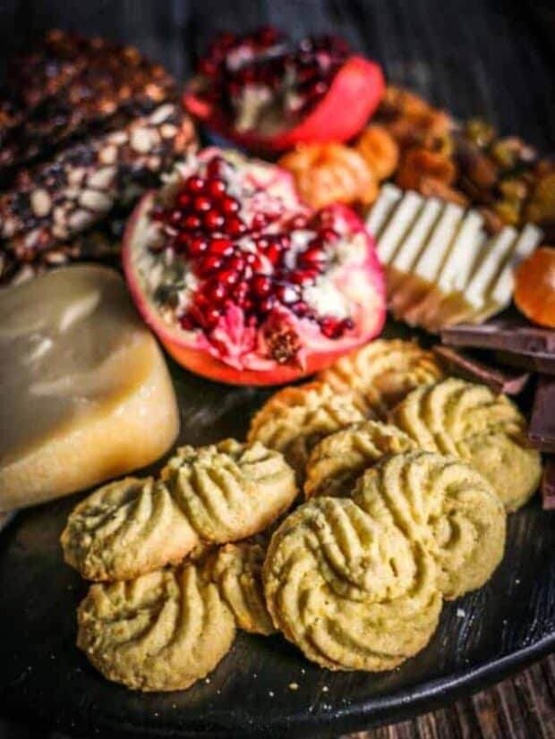 A dessert inspired cheeseboard with Gluten Free Italian Polenta Cookies, cheeses, fresh pomegranate, pan forte wedges, dried fruits, and nuts