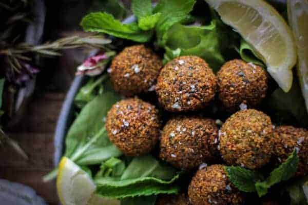 8 golden falafel on a bed of greens with lemon wedges