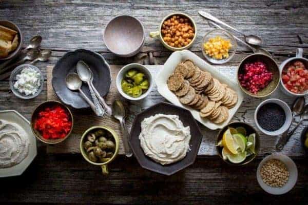 A table top spread of small bowls filled with hummus and toppings