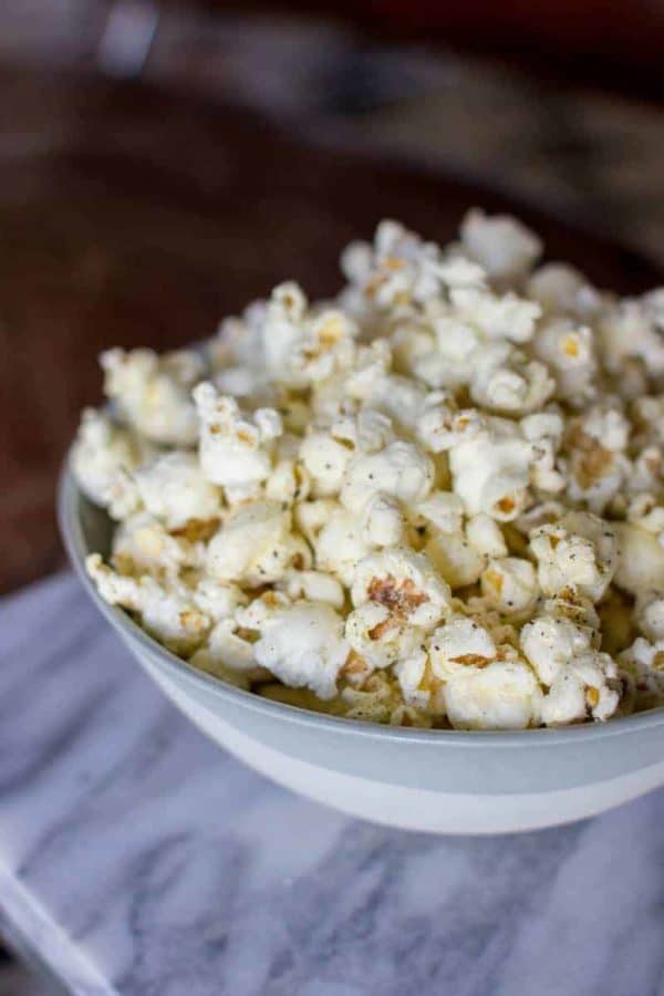 A big bowl of cacio e pepe popcorn sits on a marble table top.