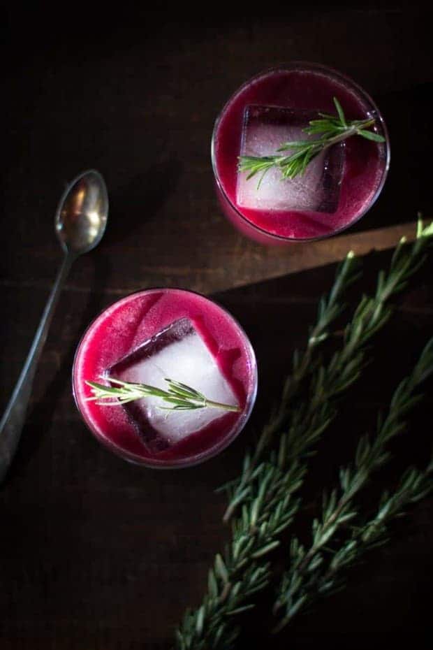 2 Stunning Rosemary Concord Grape Cocktails on a table