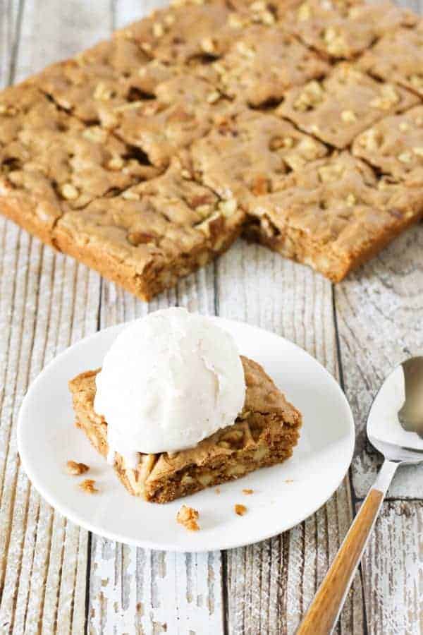 maple walnut blondies in the background with one plated blondie topped with ice cream in front