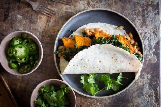A taco filled with sweet potato, white beans, and greens