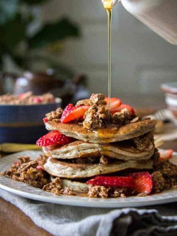 stack of pancakes with chocolate granola sprinkled over top and in batter, and strawberries
