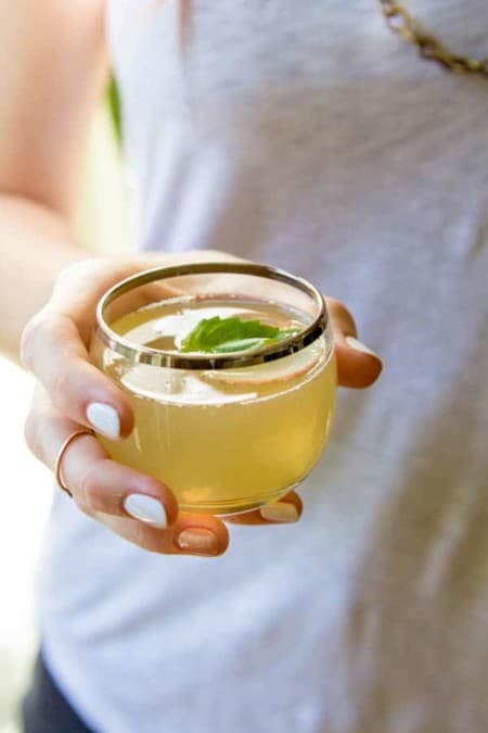 A woman holding a Apple Basil and Prosecco Spritzer 