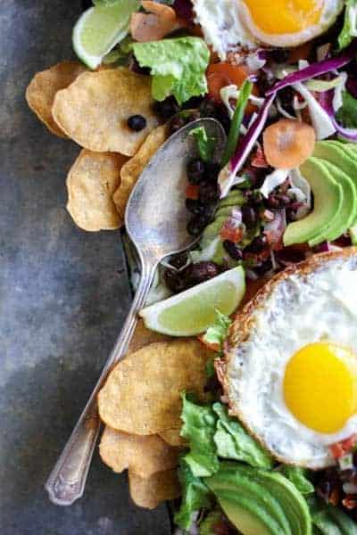 fried eggs a top salad greens with black beans, salsa, and avocado
