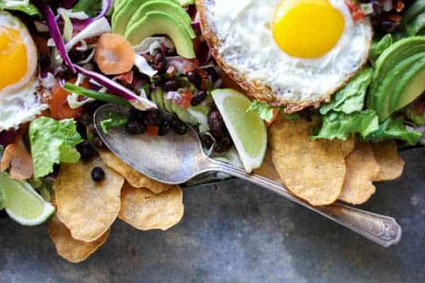 fried eggs a top salad greens with black beans, salsa, and avocado