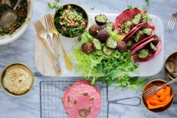 Falafel Tacos on a serving board next to tabbouleh and pink tortillas