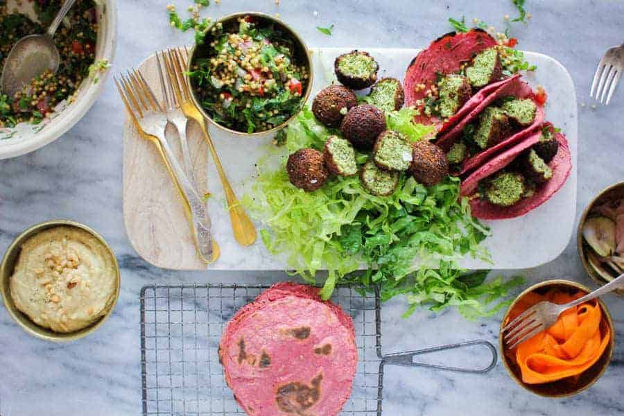 Falafel Tacos on a serving board next to tabbouleh and pink tortillas 