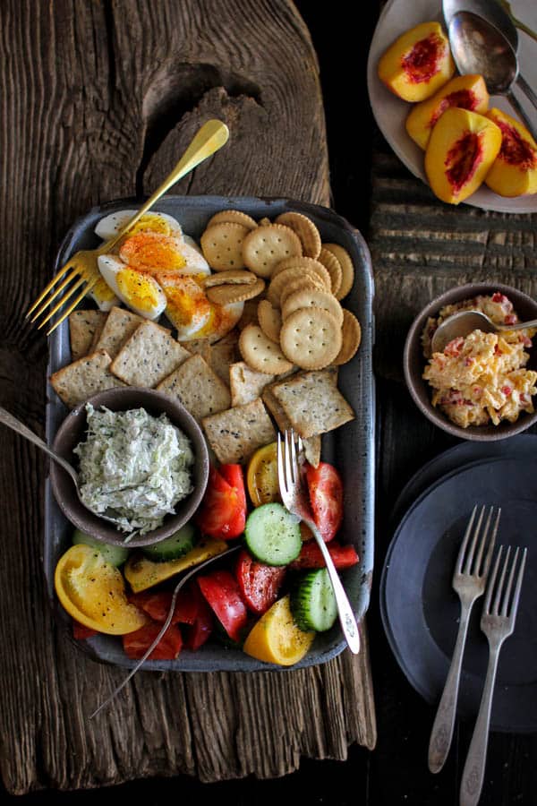 Southern Picnic Platter recipe || This picnic platter transports me back to summers growing up in the south. Homemade pimento cheese, benedictine spread, a juicy heirloom tomato and cucumber salad, fresh peaches, spice dusted hard boiled eggs, and a variety of crackers! My grandmother would have been proud of this one! || @thismessisours