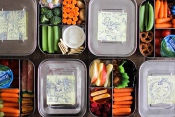 4 colorful bento boxes laid right next to each other with lunchbox drawings
