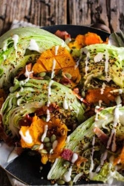 iceberg lettuce wedges with roasted butternut squash, crispy quinoa, bacon, and a ranch drizzle