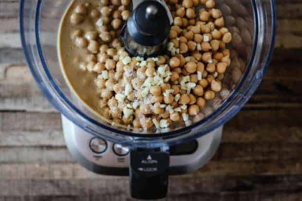 top down view into a food processor with chickpeas, chopped garlic,and seasonings.