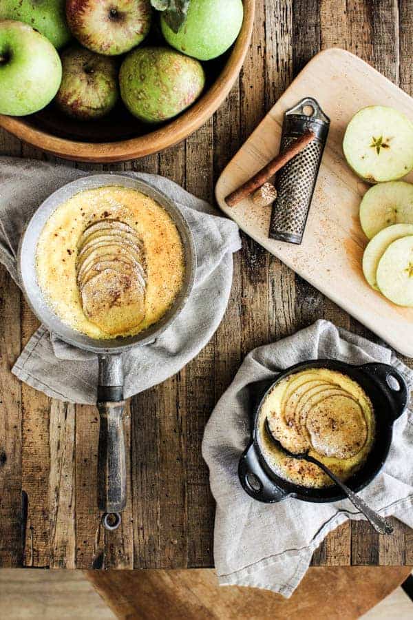 Baked apple custard on table with sliced fresh apples and cinnamon sticks