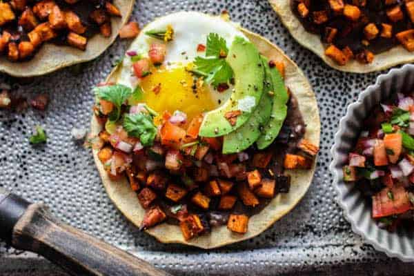 tostada with refried black beans, roasted sweet potatoes, fried egg, and avocado