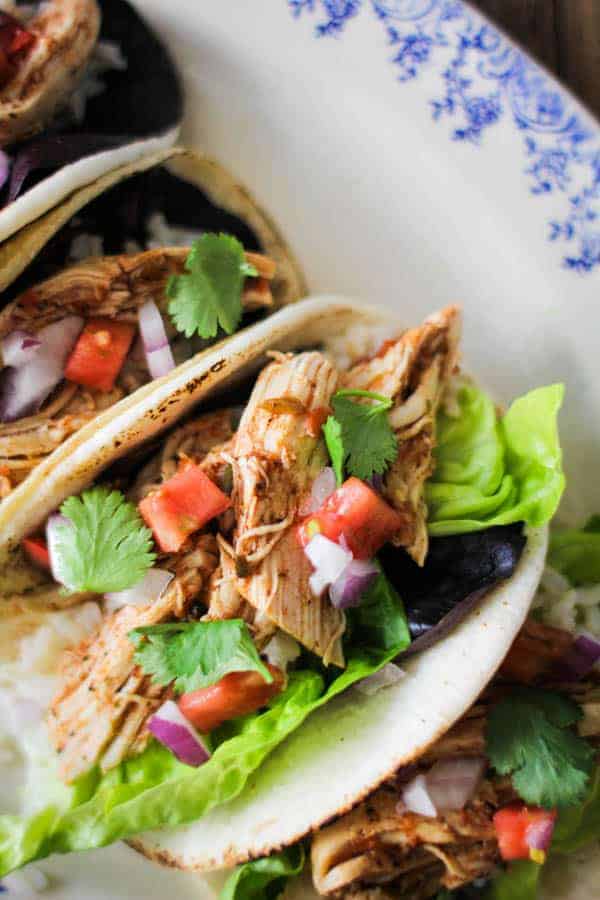 shredded salsa chicken tacos with tomato, lettuce, cilantro, and red onion