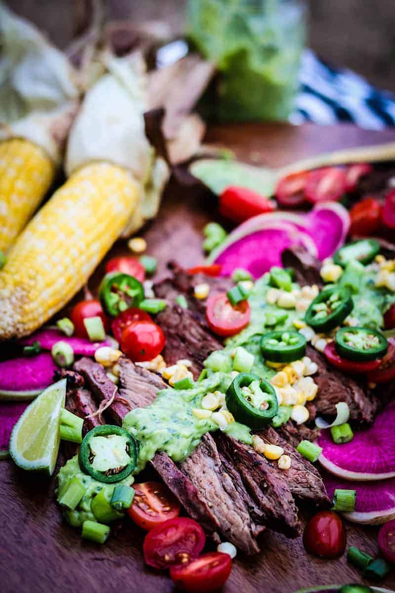 sliced grilled flank steak topped with green goddess sauce and fresh veggies