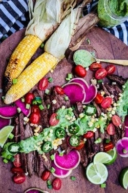 sliced grilled flank steak topped with green goddess sauce and fresh veggies