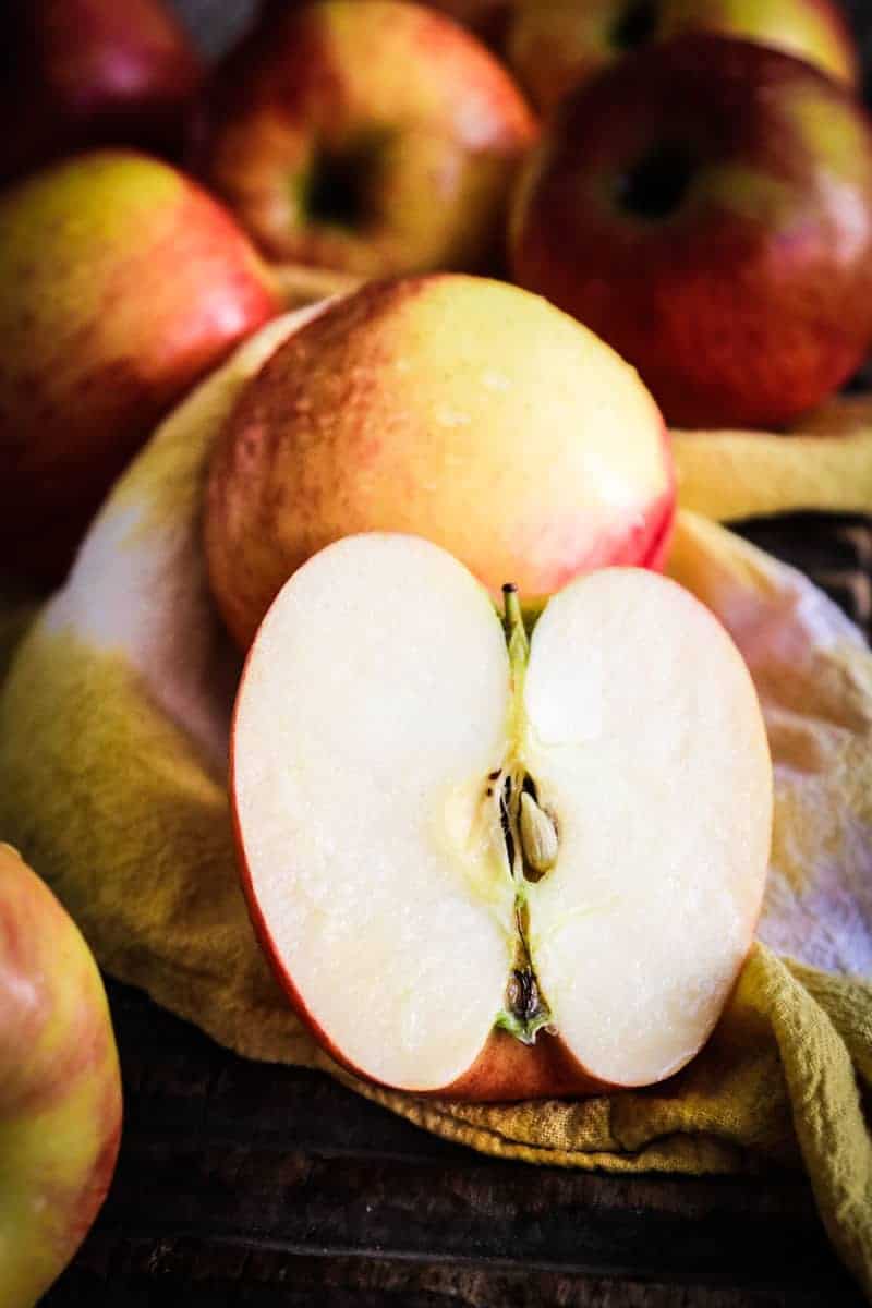 apples on a board with one sliced apple in front