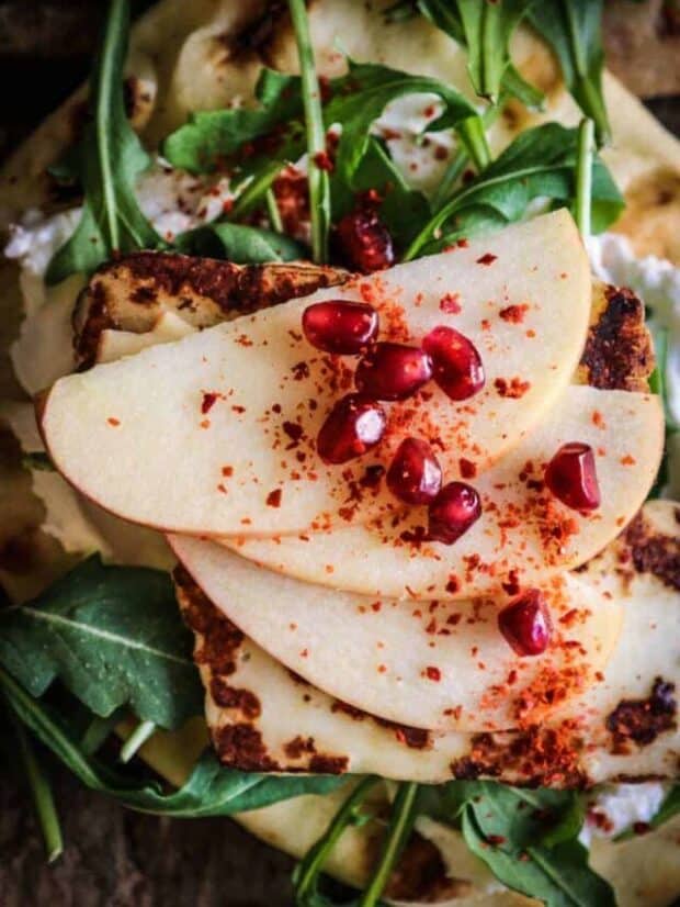 naan layered with labneh, arugula, halloumi cheese, thinly sliced apples, pomegranate, and aleppo pepper