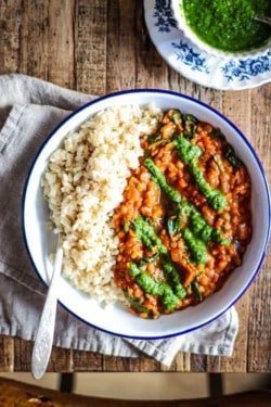 bowl of brown rice with red lentil coconut curry and drizzled with green cilantro chutney