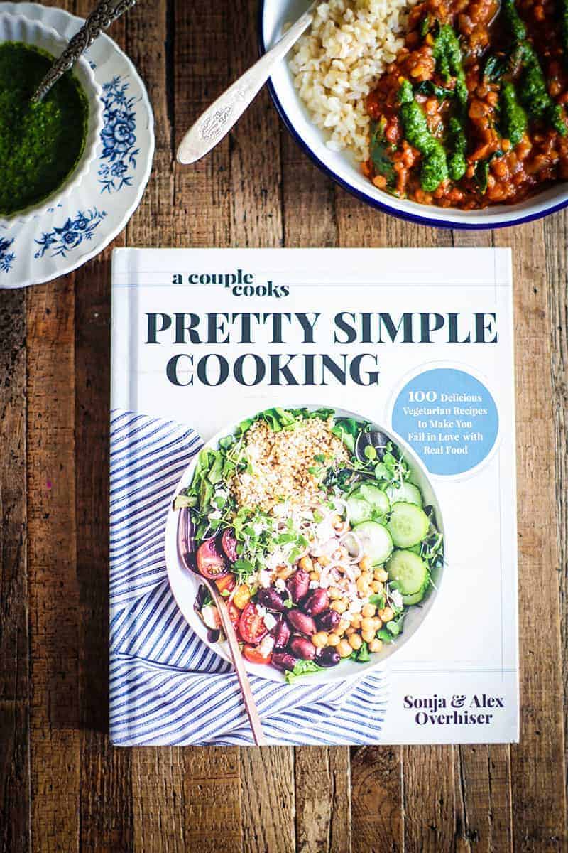 A bowl of curry and a bowl of chutney with a copy of teh cookbook Pretty Simple Cooking