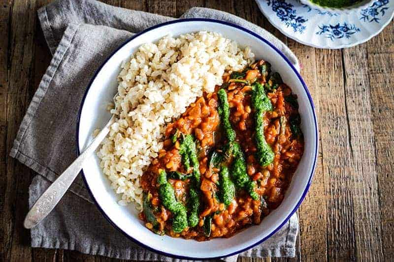 bowl of brown rice with red lentil coconut curry and cilantro chutney drizzled on top