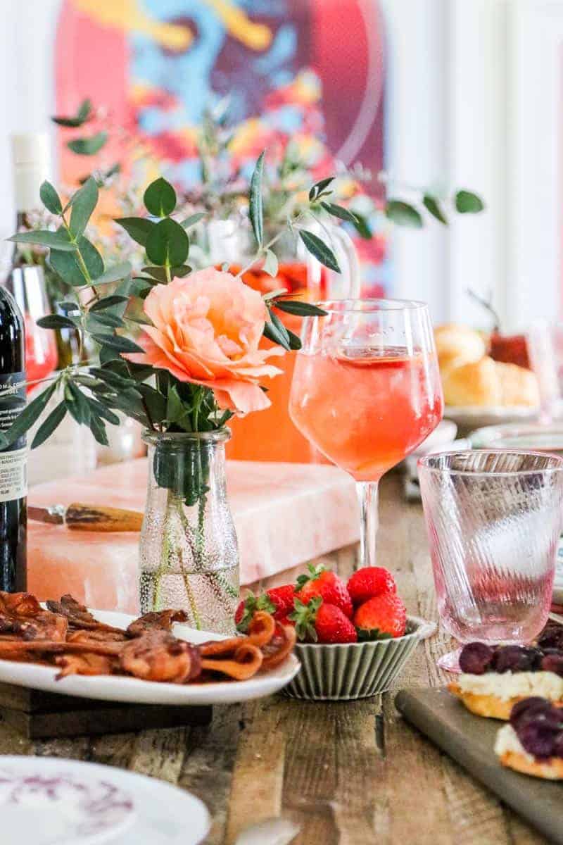 brunch table with flowers, sangria, strawberries, and bacon