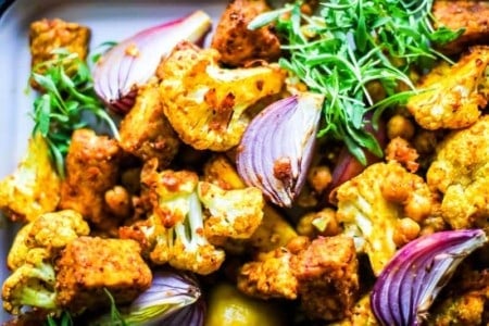 marinated chunks of tempeh, on a sheet pan with roasted cauliflower, chickpeas, onion wedges, and lemons.