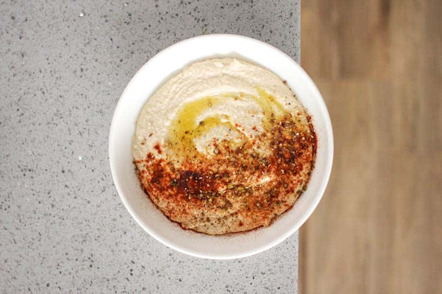 bowl of homemade hummus with a drizzle of olive oil and hearty sprinkle of paprika