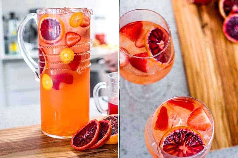 Pitcher and glasses of Blood Orange Ginger Sangria with fresh oranges, strawberries, raspberries and kumquats