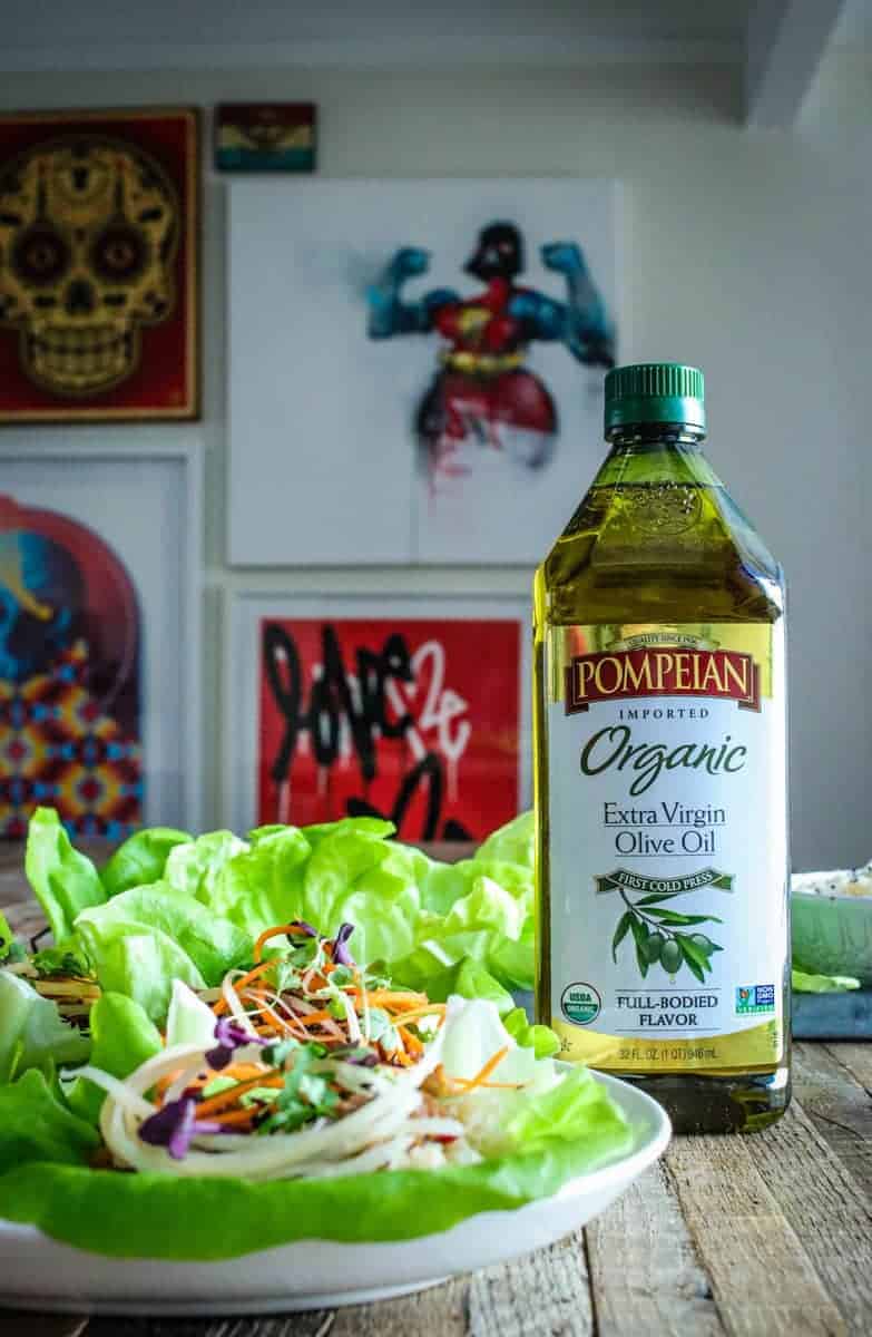 lettuce cups with brown rice, hoisin mushroom filling, shredded carrots, micro greens, and sesame seeds. Next to a bottle of Pompeian olive oil