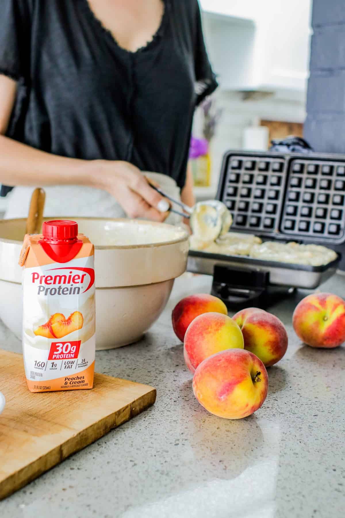 cooking waffles in a waffle iron with fresh peaches and Premier Protein Peaches and cream shake