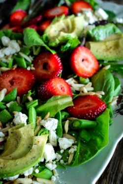 Salad of baby greens, sliced strawberries, avocado, snap peas, toasted almonds, and feta with a strawberry poppyseed dressing.