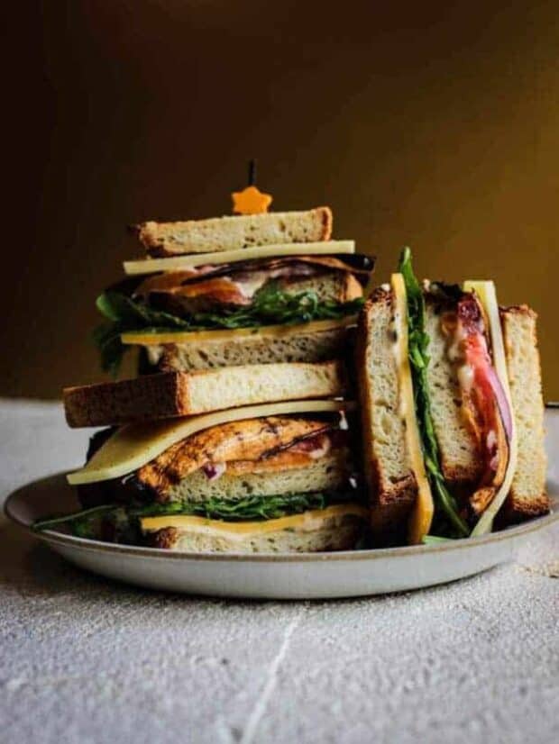3 halves of ultimate vegetarian club sandwich stacked on a plate.