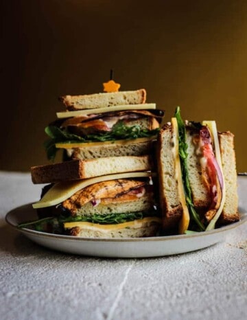 3 halves of ultimate vegetarian club sandwich stacked on a plate.