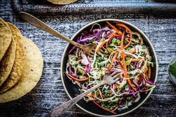 A bowl of Tex Mex Rainbow slaw next to a stack of corn tostadas