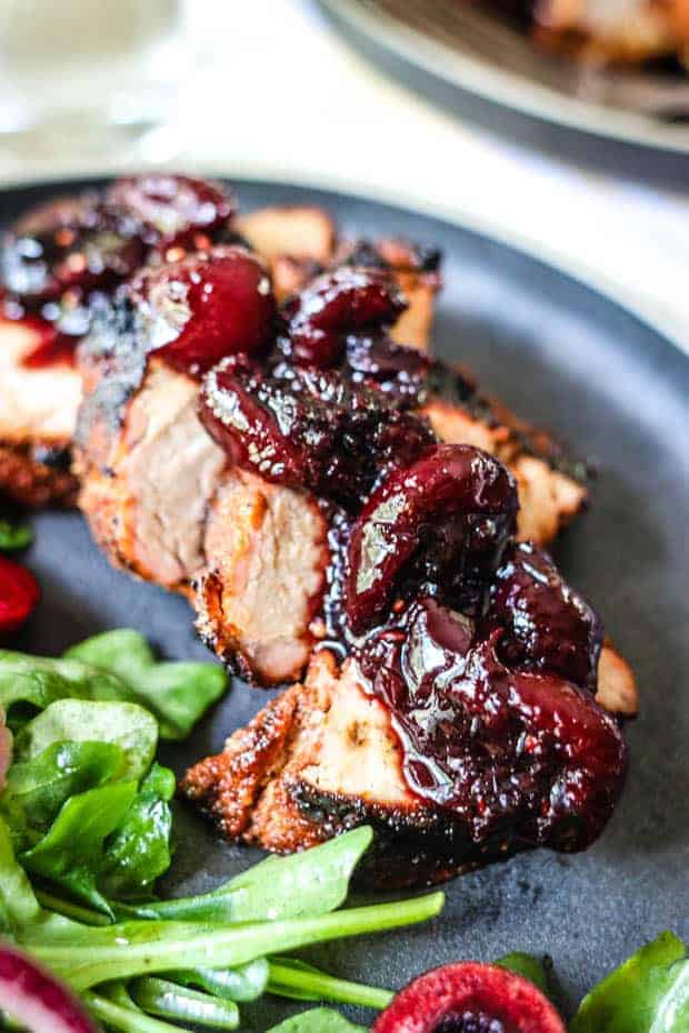 A close up shot of slices of pork tenderloin topped with cherry ginger chutney.