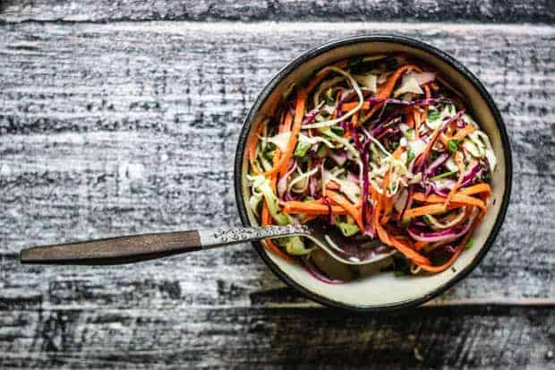 A bowl of colorful slaw on a table top. 
