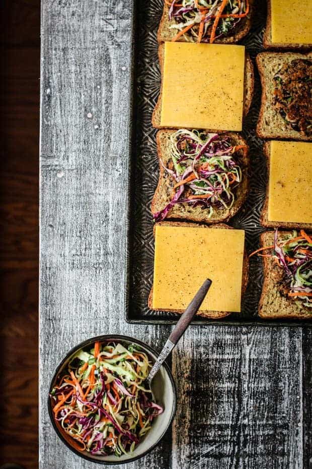 A sheet pan of prepped oats melts o a table next to a bowl of slaw.