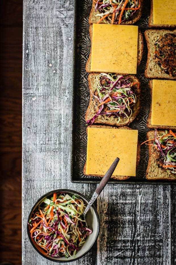 A sheet pan of prepped oats melts o a table next to a bowl of slaw.