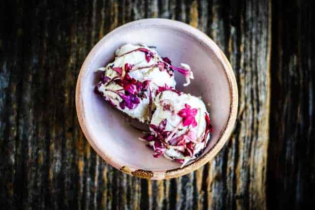 A small ceramic pink bowl with 2 goat cheese balls rolled in edible flowers