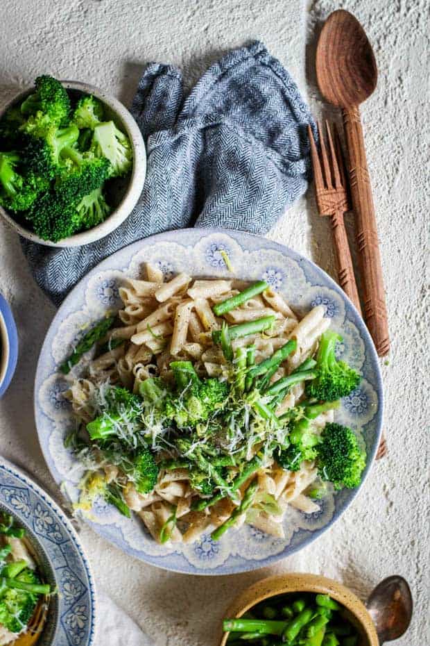 A ig bowl of lemon cream pasta with vibrant green veggies on top.