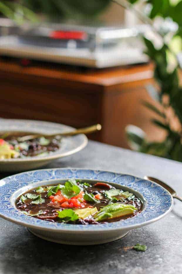 2 bowls of Instant Pot Black Bean Soup topped with salsa, avocado, and cilantro leaves