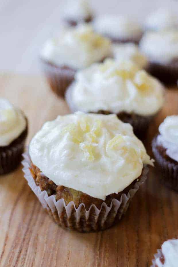 Close up of iced Easy Gluten Free Carrot Cake Muffins with cream cheese frosting and iced candied ginger garnishes